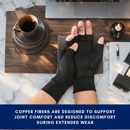 Person wearing black copper fiber gloves on a desk with a laptop and coffee.